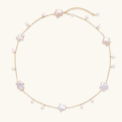 Gold vermeil chain with iridescent star-shaped baroque pearls and small round freshwater pearl drops on cream background.