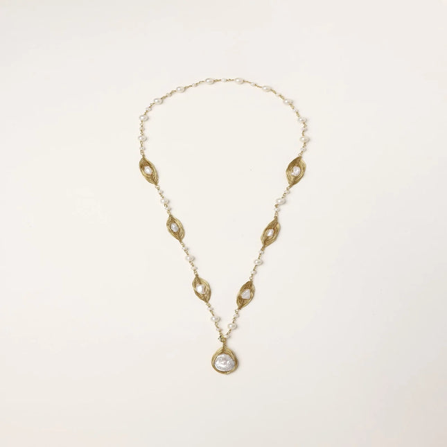 14K gold-plated necklace with eye-shaped stations and baroque pearl pendant on cream background