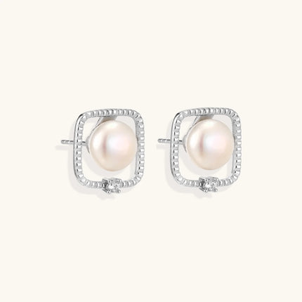 Rhodium-plated silver stud earrings with cushion frame, centered freshwater pearl, and tiny crystal accent