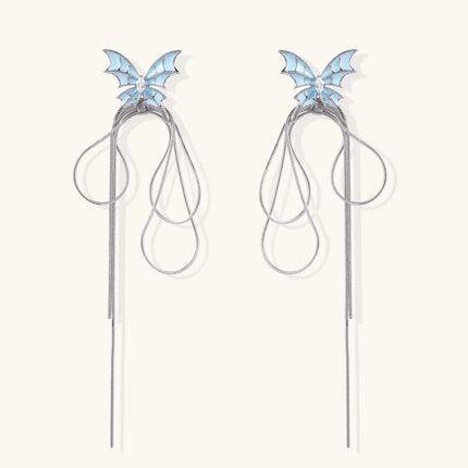 Long silver-tone earrings with powder blue enamel butterfly studs and flowing chain tassels on cream background
