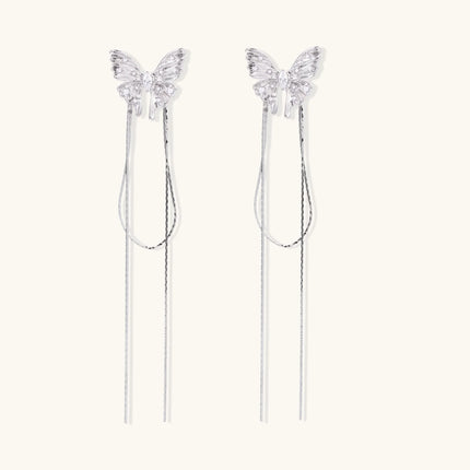 Pair of silver threader earrings with crystal butterfly tops and long chain drops on cream background.
