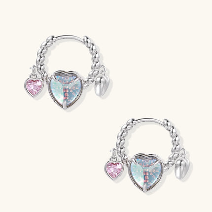 Silver chain hoop earrings with iridescent opal heart charms and pink zirconia accents on white background