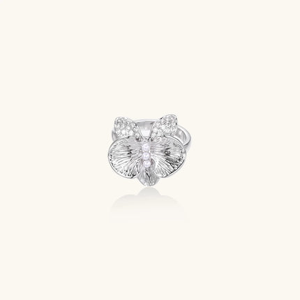Silver-toned orchid ring with textured petals, pearl center accents, and sparkling zirconia stones on white background.