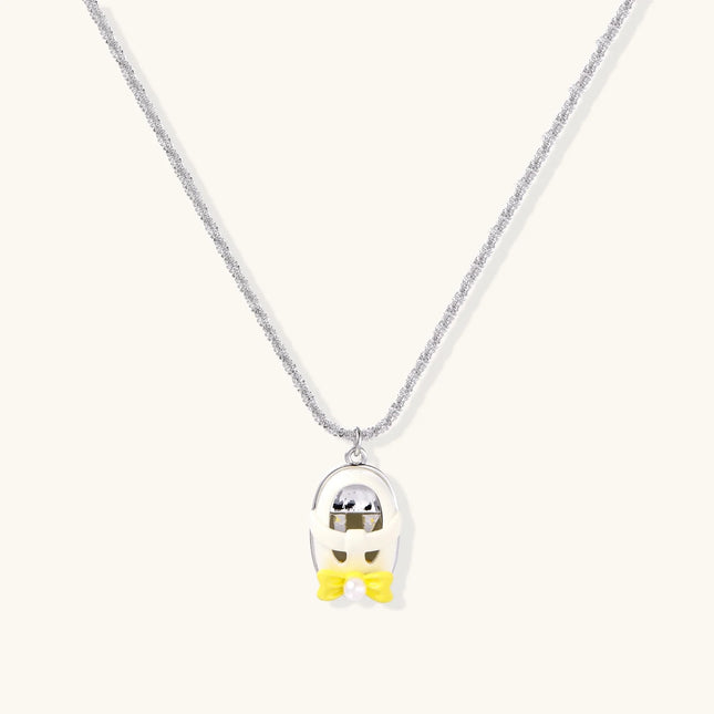Chrome egg-shaped pendant with kawaii face, yellow bow, and pearl detail on silver chain against white background