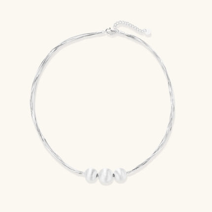 Sterling silver multi-strand necklace with three brushed round beads on cream background