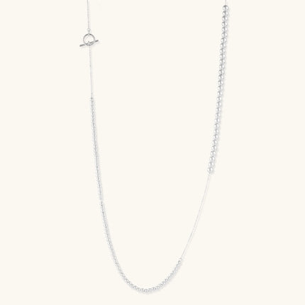 Long sterling silver beaded necklace with graduated sphere design, toggle clasp, and delicate chain extension on white background