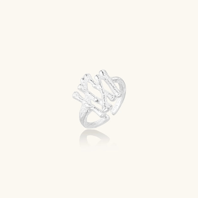 Sculptural sterling silver ring with organic branch design and textured surfaces on cream background
