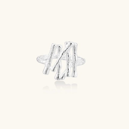Sculptural sterling silver ring with organic branch design and textured surfaces on cream background