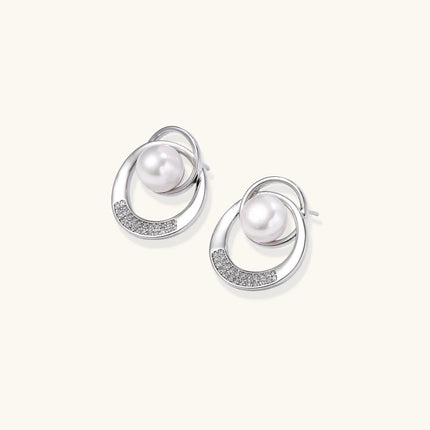 White gold-plated brass earrings with circular design, freshwater pearl center, and diamond accents