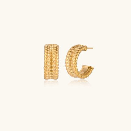 Chunky gold hoops with dimensional ridged texture and 14K plated finish shown in front and side view on cream background.