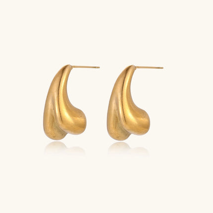 Pair of sculptural gold stud earrings with twisted organic forms on cream background