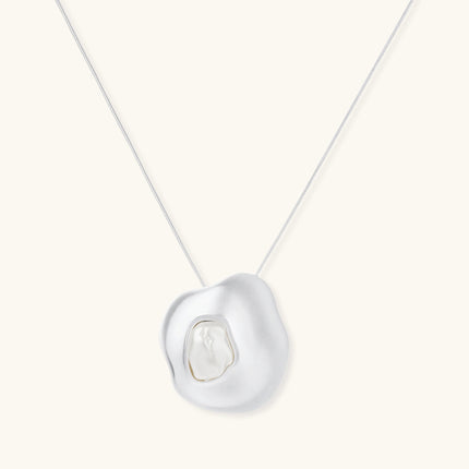 Organic-shaped gold pendant necklace with baroque pearl accent on adjustable chain, displayed against neutral background.