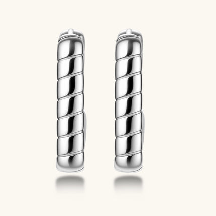 Close-up of platinum-plated sterling silver hoop earrings with horizontal textured grooves on white background.