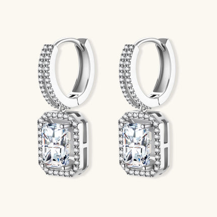 Sterling silver huggie hoops with emerald-cut moissanite drops featuring pavé-set crystals on white background.